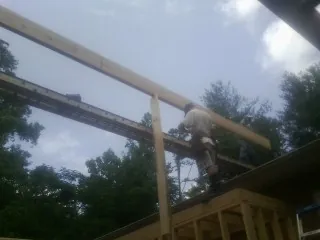 Carpenter setting a ridge beam over a new addition frame — Ice Dam Removal by Roofing Brothers in East Northport