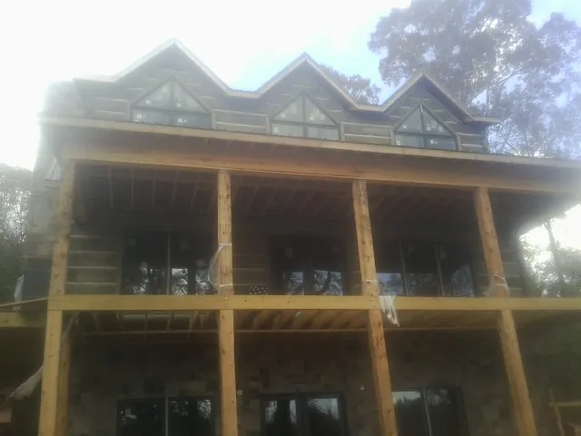 Dormers and porch framing on a large log home under construction — Roof Coating work by our crew in East Northport