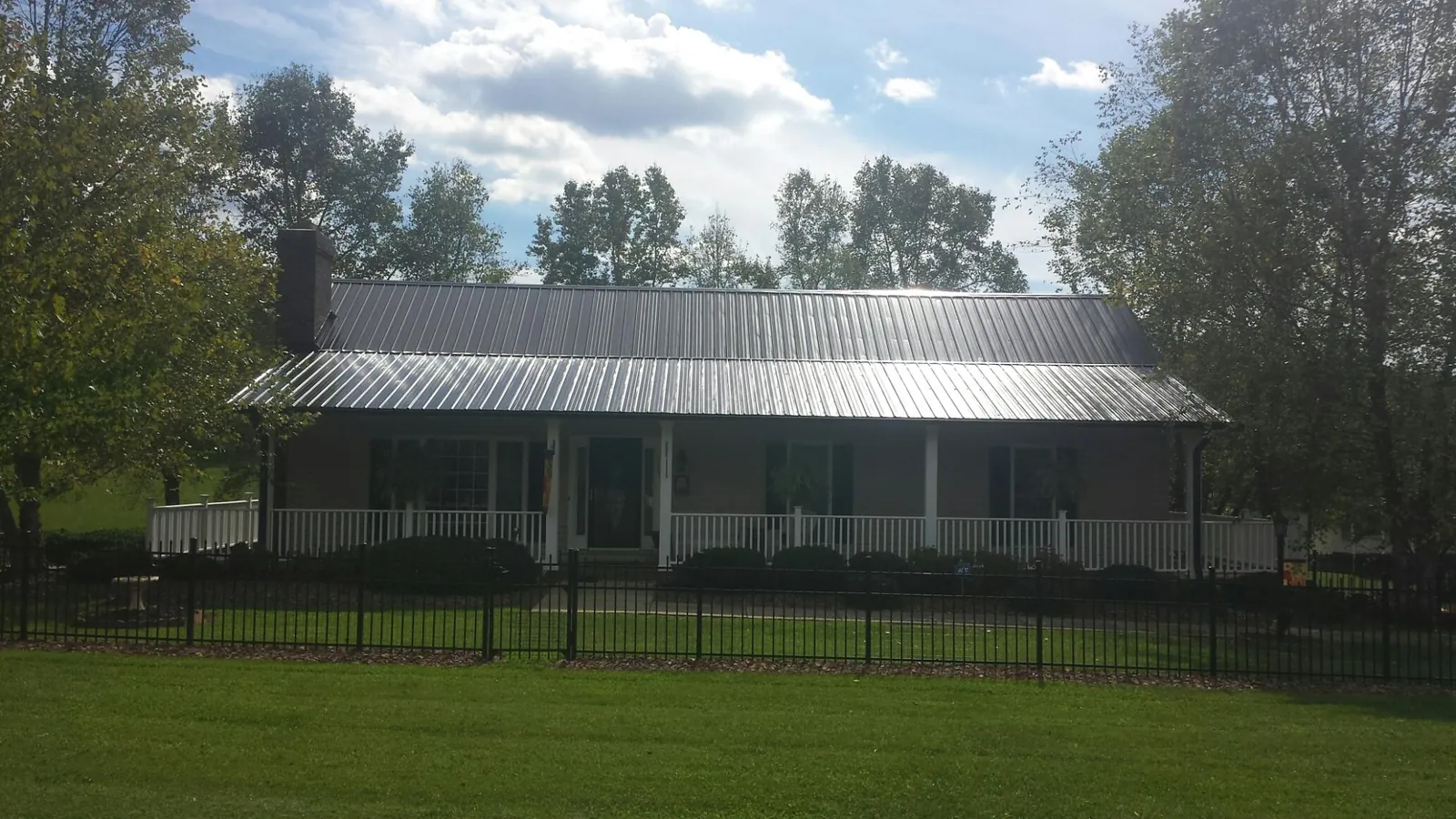 Gray metal roof on a brick ranch with a full width front porch — Gutter Guard Installation work by our crew in East Northport