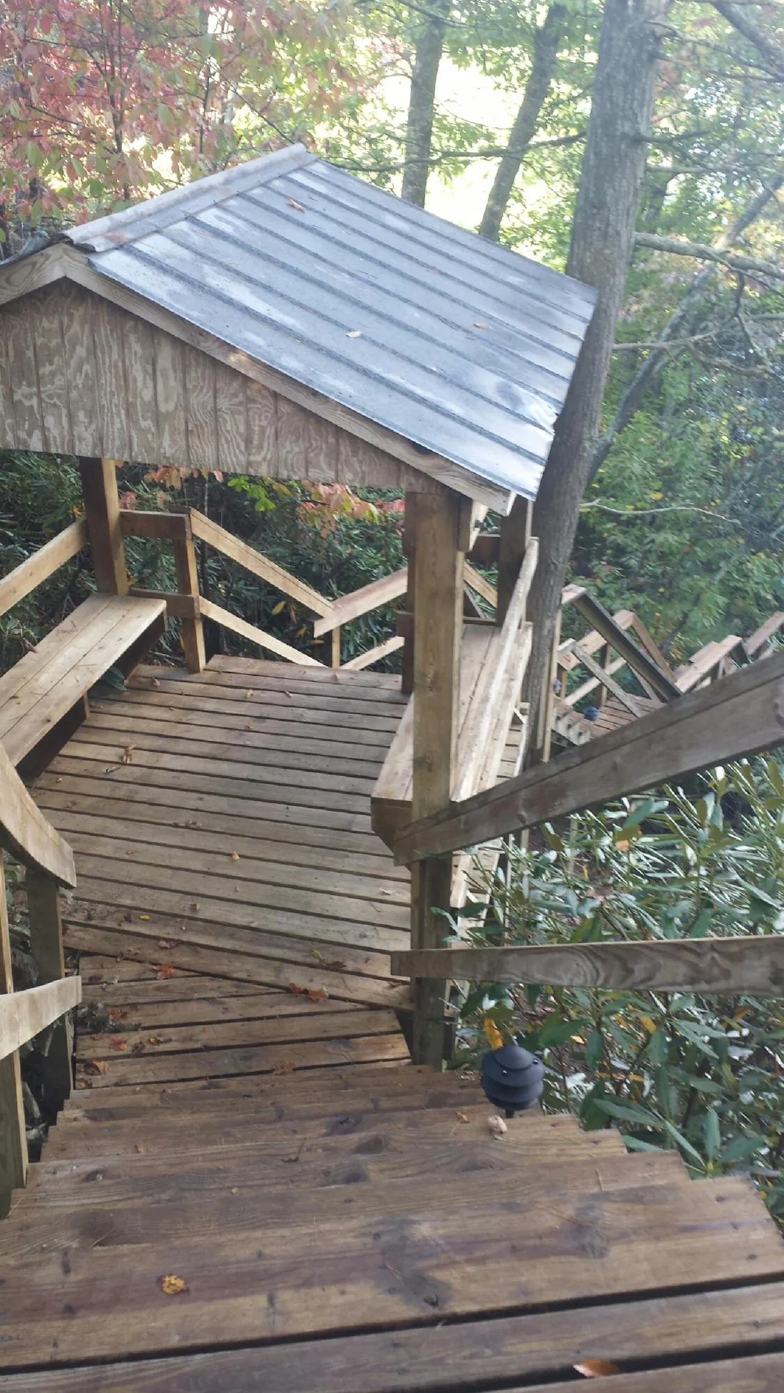 Metal roofed shelter over wooden steps on a wooded walkway — Skylight Repair & Installation work by our crew in East Northport