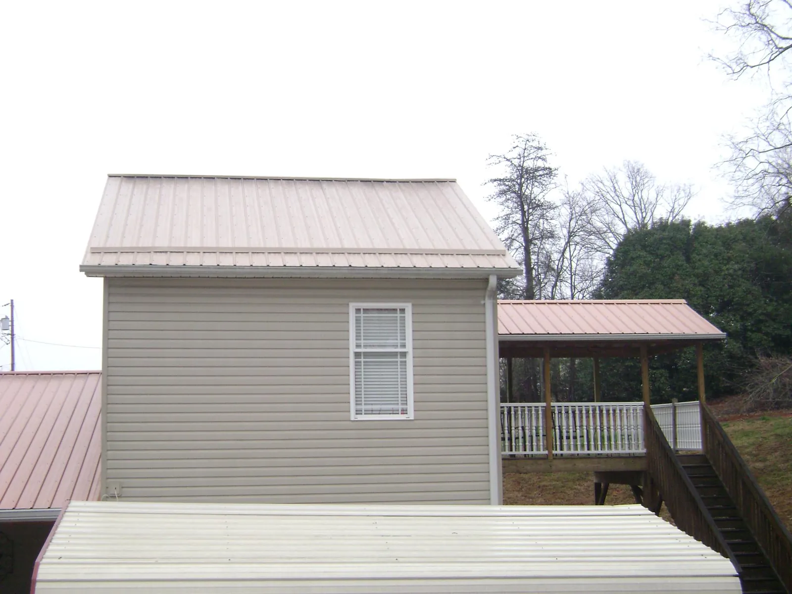 Tan metal roofs on a two story addition and attached porch, from a Roof Replacement job in East Northport