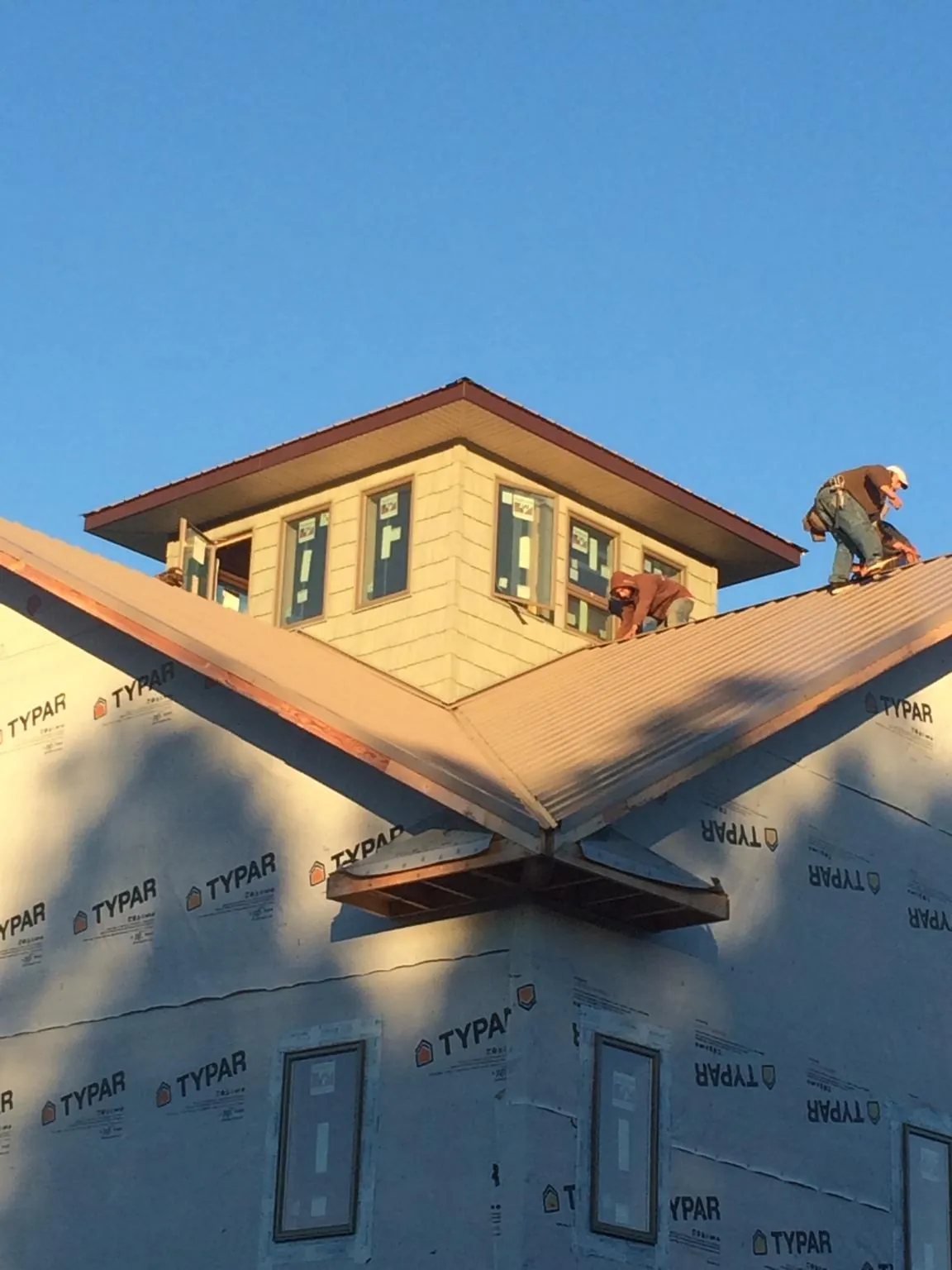 Roofers working around a rooftop cupola on a new metal roof at sunset — Roof Waterproofing in East Northport by Roofing Brothers